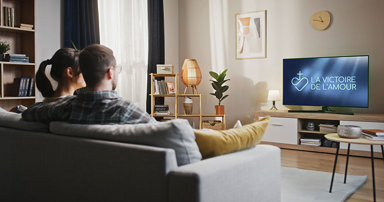 Couple regardant l'émission La Victoire de l'Amour à la télévision